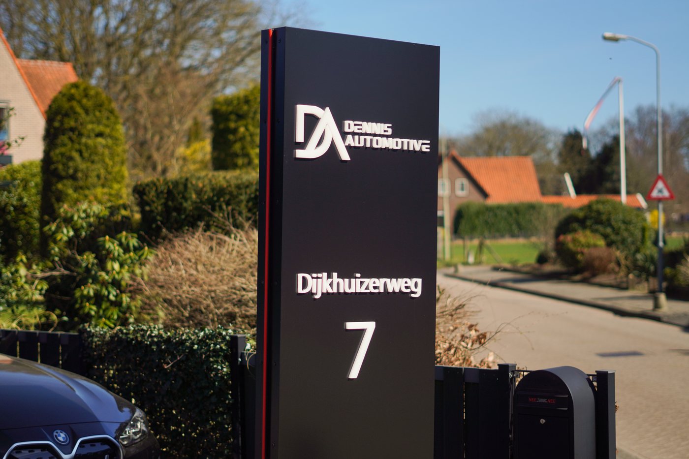 Zuil met logo en adres Dijkhuizerweg 7 voor het pand van Dennis Automotive